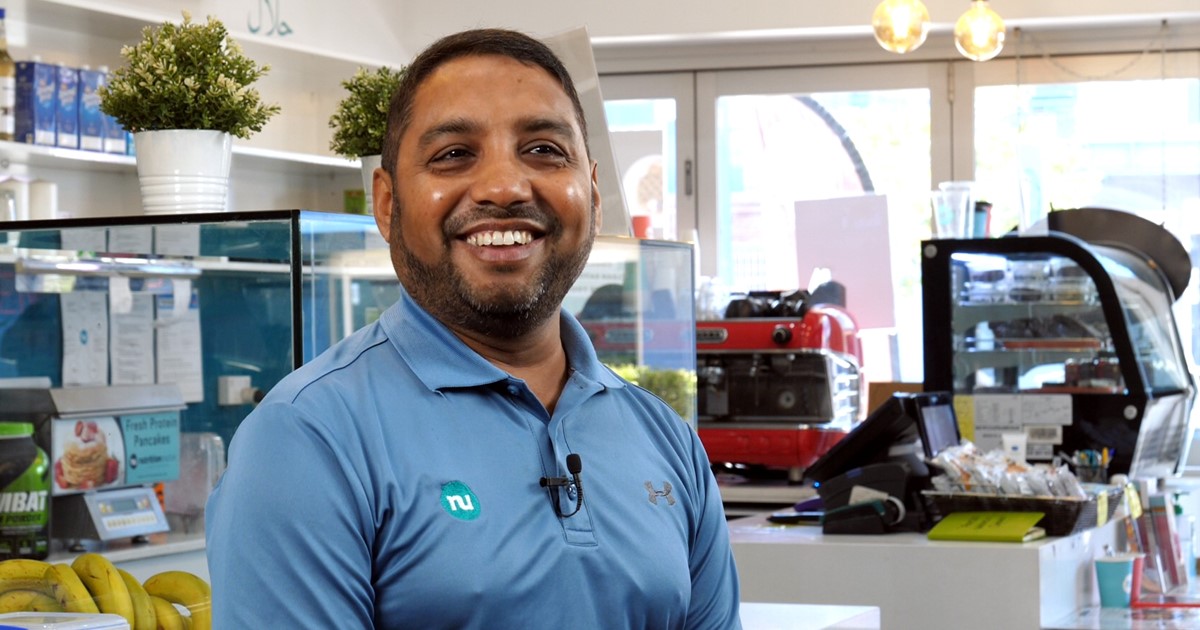 Male small business owner smiling at a cafe
