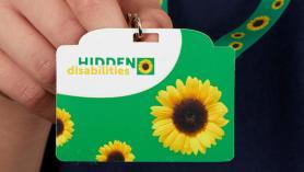 Person holding sunflower hidden disabilities badge and lanyard